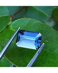 3.90 ct. untreated GIA Certified loose Sapphire Blue Changing to Purple held by tweezers on a green leaf