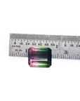 A brazilian tourmaline next to a ruler on a white background.