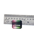 Loose 6.55 ct. emerald-cut watermelon tourmaline, red to green, next to a ruler.