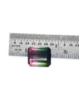 Loose 6.55 ct. emerald-cut watermelon tourmaline, red to green, next to a ruler.