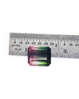 Loose 6.55 ct. emerald-cut watermelon tourmaline, red to green, next to a ruler.