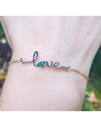 A Love bracelet white and yellow gold with a round cut natural Colombian emerald on a wrist.