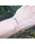 Emerald Love Bracelet in 14K yellow and white gold with a round cut emerald, worn on a wrist.