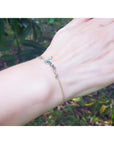 Emerald Love Bracelet in 14K yellow and white gold with a round cut emerald, worn on a wrist.
