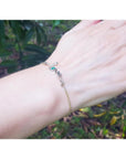 Emerald Love Bracelet in 14K yellow and white gold with a round cut emerald, worn on a wrist.