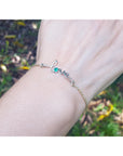 White and yellow gold bracelet with a natural emerald on a wrist against a natural background.