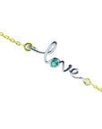 A bracelet with 'LOVE' center piece featuring a round cut emerald on a topside view.