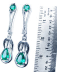 Pair of genuine Love Knot emerald earrings next to a ruler for scale on a white background.