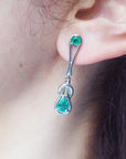 White gold Love Knot emerald earring worn by a person