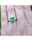 1.27 ct natural Colombian emerald three-stone ring in 18K yellow gold with two trillion-cut diamonds.