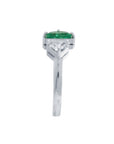 The emerald showcases fine quality with its distinctive fancy cut, while the geometric trillion diamond creates striking visual contrast.