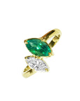 You and Me ring showcases a marquise-cut emerald paired with a natural diamond accent, all set in 18K yellow gold.