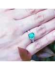 Vista cercana de una mano mostrando un anillo con esmeralda colombiana para mujer hecho en oro de 18k blanco.