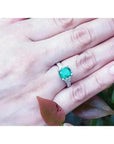Anillo de compromiso de oro blanco con esmeralda colombiana y diamantes trapezoidales en mano.