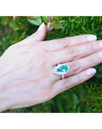 Anillo de oro 14k con esmeralda colombiana verde azul corte pera 3.35 ct rodeada de diamantes en mano.
