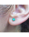 An earlobe wearing a martini emerald stud earring in white gold.