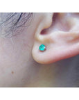Martini emerald stud earring with a round cut medium deep green emerald in 14K white gold on an ear.
