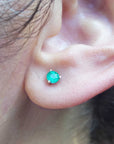 An earlobe wearing a martini emerald stud earring