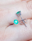 Displaying on a hand a pair of push backs martini emerald stud earrings.