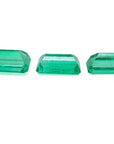 Three emerald-cut natural Colombian emeralds, a matched set for earrings and pendant, on a white background.