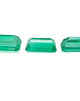 Three emerald-cut natural Colombian emeralds, a matched set for earrings and pendant, on a white background.
