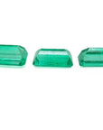 Three emerald-cut natural Colombian emeralds, a matched set for earrings and pendant, on a white background.