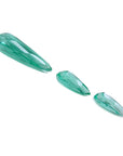 Three sparkling pear-shaped Colombian emeralds, one large and two smaller, on a white background.