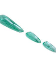 Three sparkling pear-shaped Colombian emeralds, one large and two smaller, on a white background.