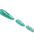 Three sparkling pear-shaped Colombian emeralds, one large and two smaller, on a white background.