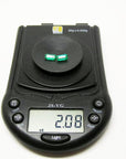Matched pair of 2.08 ct. natural emerald-cut emeralds on a black digital scale.