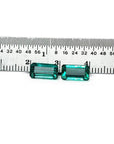 Emerald-cut 3.38 ct. matching pair loose emeralds with vibrant bluish-green color, displayed next to a ruler.
