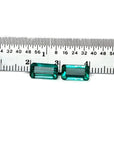 Emerald-cut 3.38 ct. matching pair loose emeralds with vibrant bluish-green color, displayed next to a ruler.