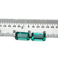 Emerald-cut 3.38 ct. matching pair loose emeralds with vibrant bluish-green color, displayed next to a ruler.
