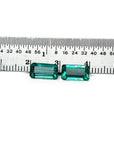 Emerald-cut 3.38 ct. matching pair loose emeralds with vibrant bluish-green color, displayed next to a ruler.