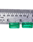 Two emerald stones next to a ruler for size measure in mm.