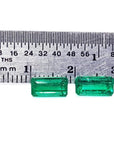 Matched pair of natural emerald-cut green emeralds next to a ruler for scale.