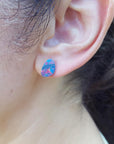 Close-up of an ear wearing a colorful Australian opal stud earring.