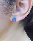 Teardrop Australian doublet opal earring with incandescent red, blue, and green flashes on an ear.