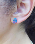 Teardrop Australian doublet opal earring with incandescent red, blue, and green flashes on an ear.