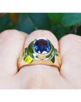 Men's 18K yellow gold ring with a bezel-set oval blue sapphire and Greek key design.