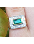 Gold mens ring with emerald and diamonds on a finger.
