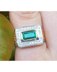 A 14k yellow gold men’s ring featuring a bezel-set natural Colombian emerald and sparkling diamonds, worn on a finger.