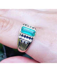 A men's emerald bezel set ring yellow 14k gold on a finger.