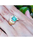 Men's 14K yellow gold horseshoe ring with a cushion-cut emerald and burnish-set diamonds.