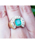 A gold men's emerald ring horseshoe design with accent diamonds on a hand.