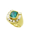 Gold horseshoe ring with a natural colombian emerald and diamond accents on a tilted position topside view.