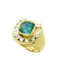 Gold horseshoe ring with a natural colombian emerald and diamond accents on a tilted position topside view.
