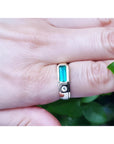 Men's 14K yellow gold ring with a deep green elongated emerald and burnish set side diamond.