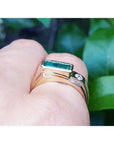 A natural colombian emerald ring for men in yellow gold being worn on a finger.