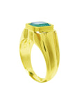Gold ring for men with a natural emerald on half side position displaying top setting and partial lateral and side view.